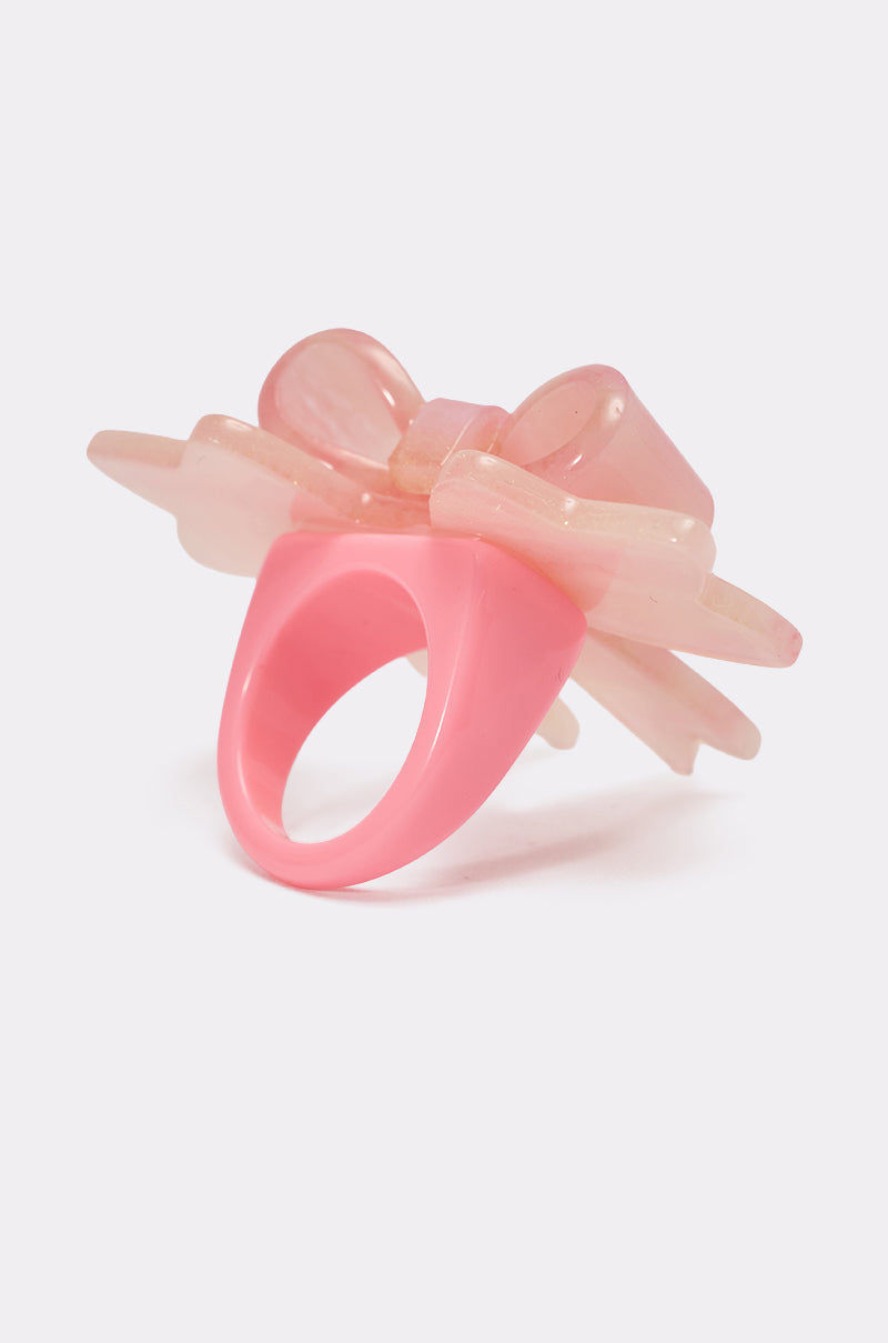 The KEKE PINK BOW RING is a chunky pink marbled statement ring with a large, translucent pastel pink bow on top, shown against a plain white background. 4
