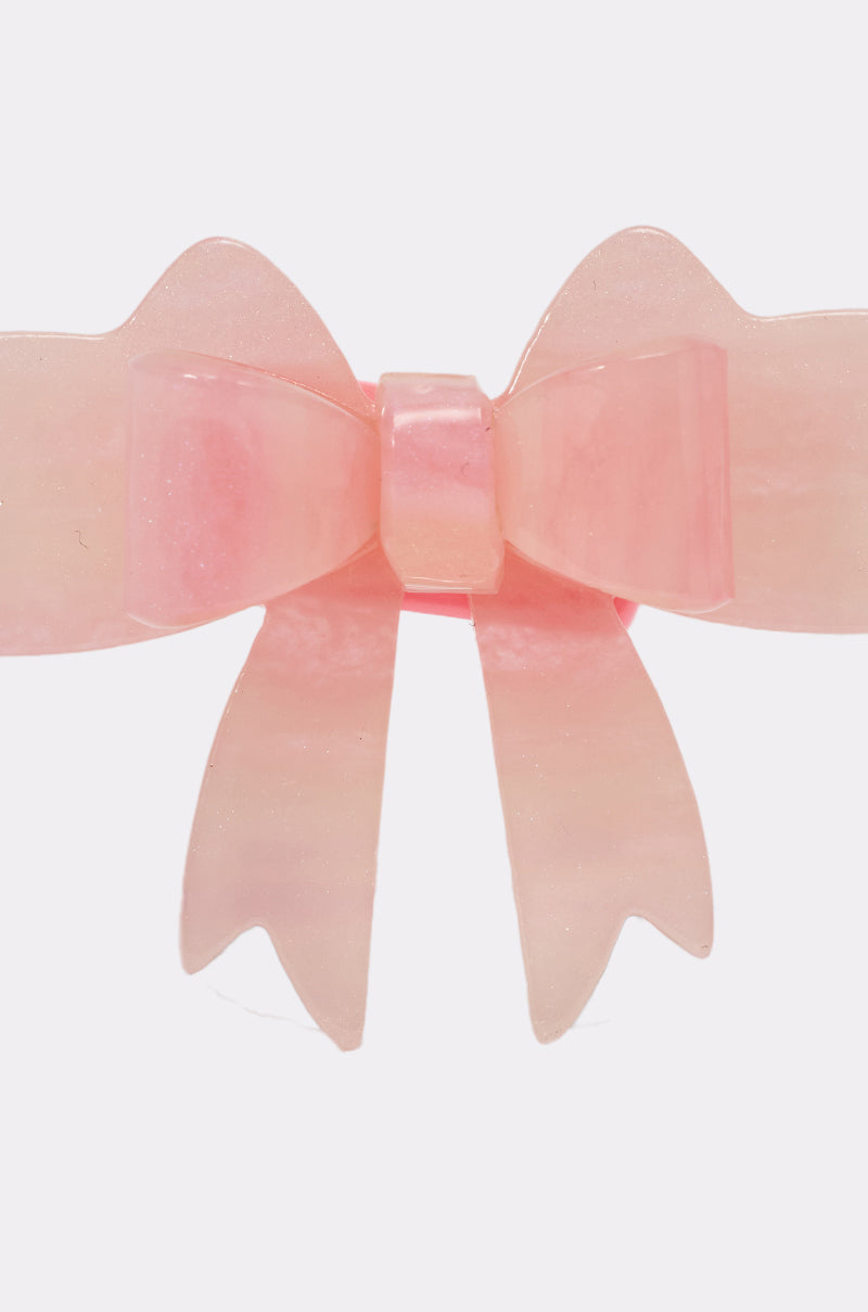 The KEKE PINK BOW RING is a shiny, translucent pink bow-shaped hair clip with pointed ribbon ends, reminiscent of a statement ring, shown against a plain white background. 5