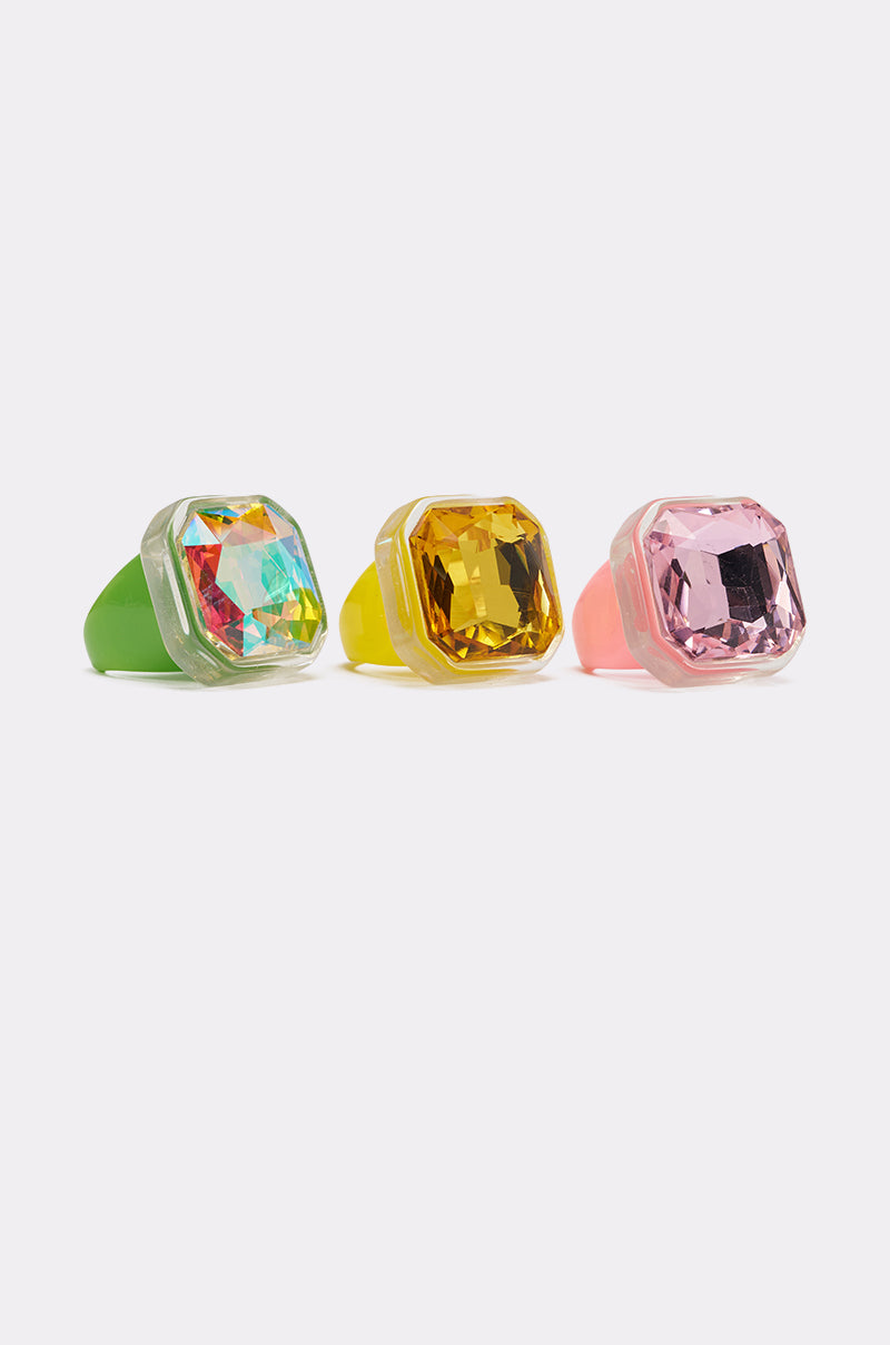 The GLINDA VIBES RING SET includes three bold acrylic rings with oversized faceted gems in iridescent, golden yellow, and light pink on colorful bands—perfect for making a statement. 0