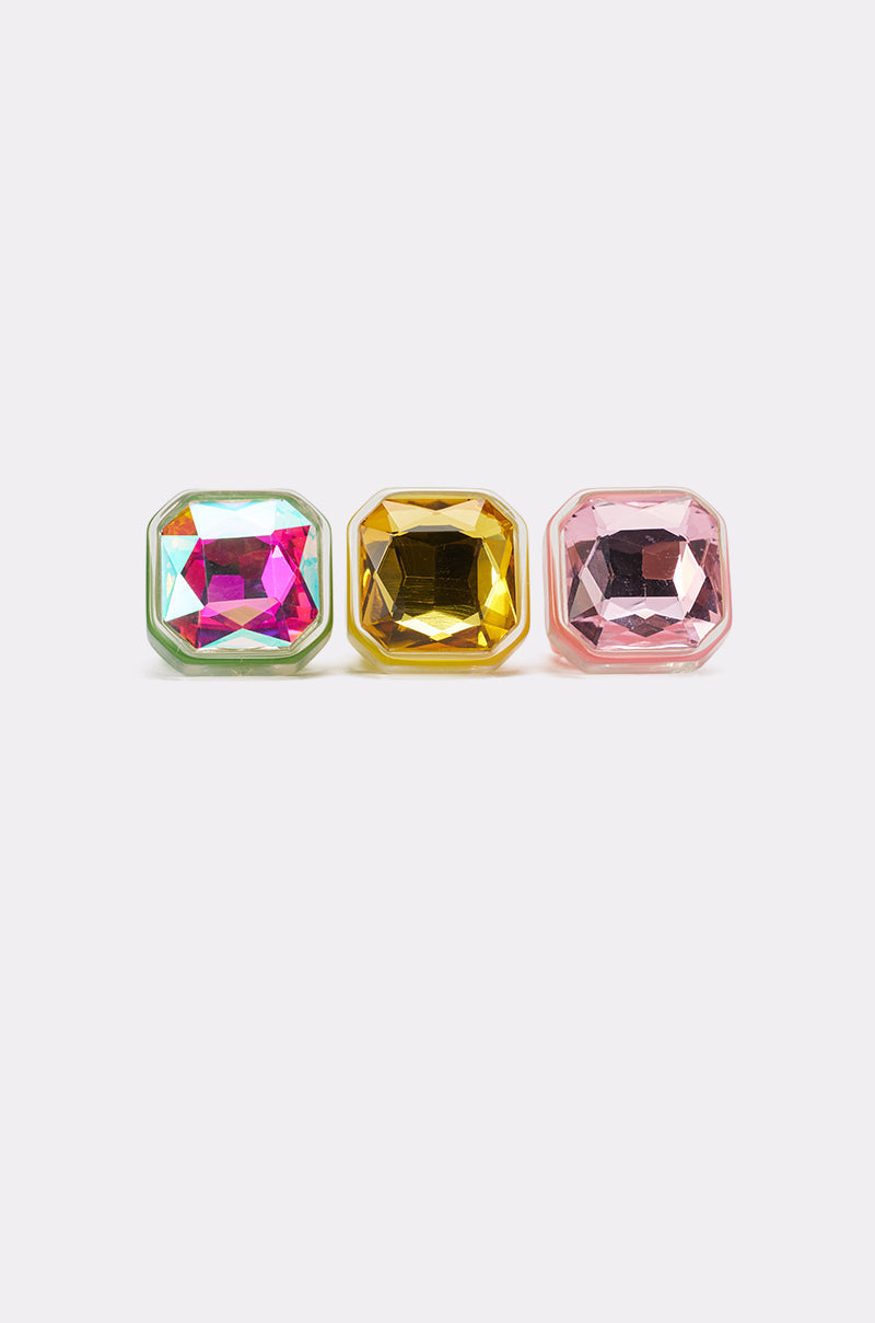 The GLINDA VIBES RING SET features three square-cut stones in green, yellow, and pink acrylic settings displayed in a row on a simple light background. 2