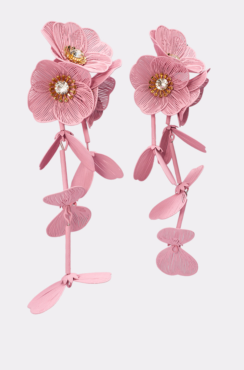 The DO TOO MUCH EARRING features pink layered flower petals, gold centers, and clear gem accents. With dangling details, these floral earrings create a delicate, elegant look set against a light gray background. 5