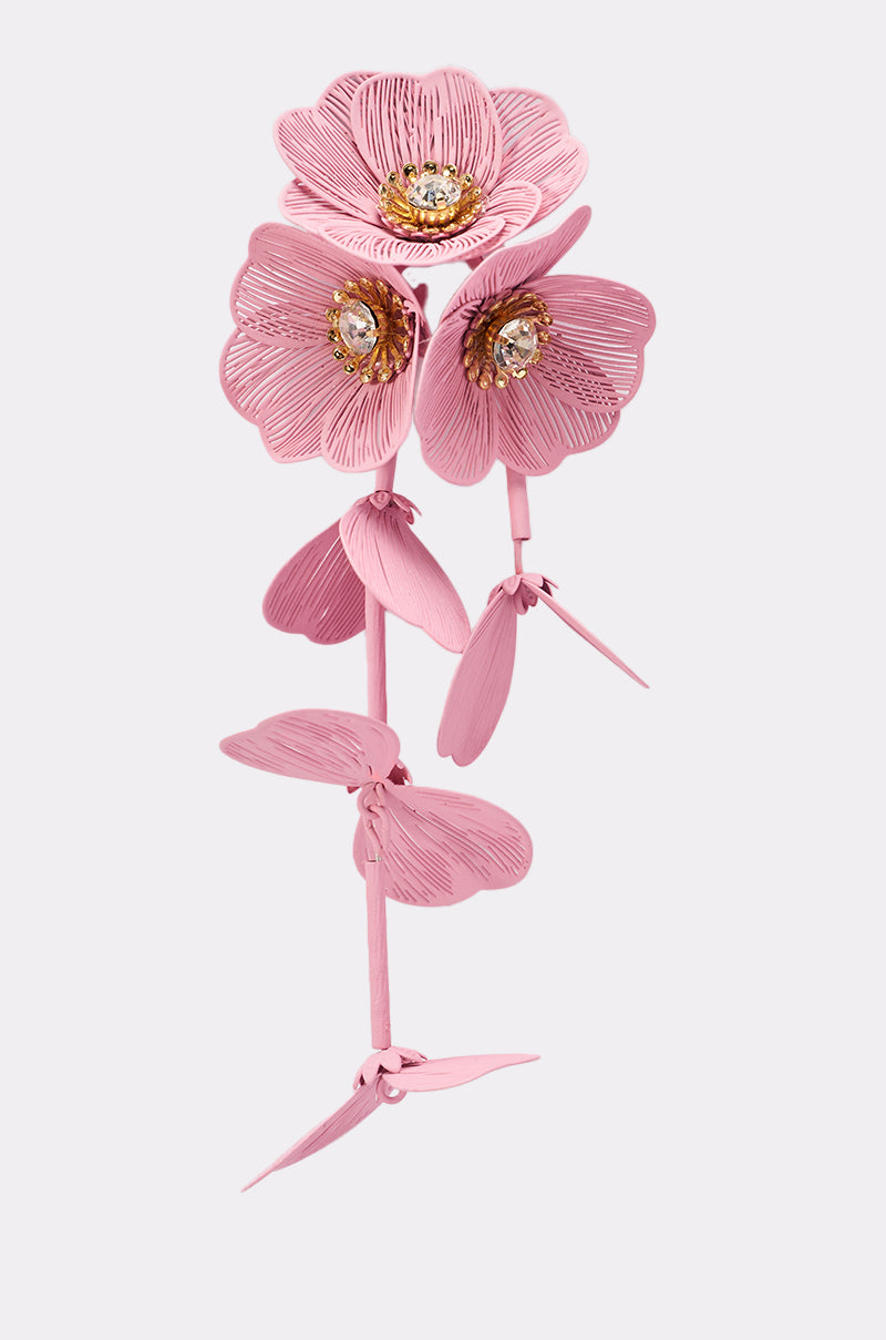 Stylized illustration of DO TOO MUCH EARRING: three pink flower earrings with textured petals and jeweled centers, on a pink stem with long leaves, set against a light gray background. 6