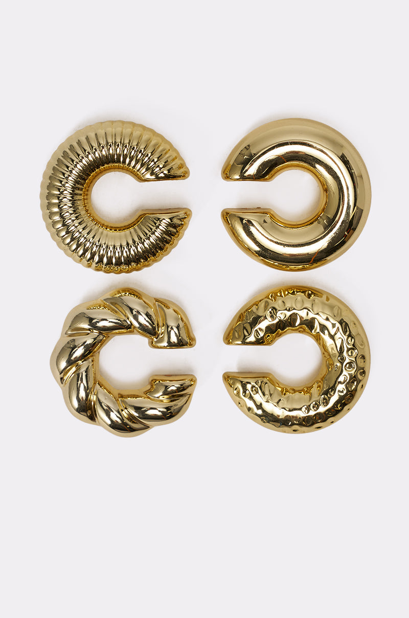 The ULTIMATE EAR CUFF SET features four gold, circular cuffs—ridged, smooth, braided, and hammered—arranged in a 2x2 grid on a light background. Ideal for a stacked-ear look with no piercings required. 1