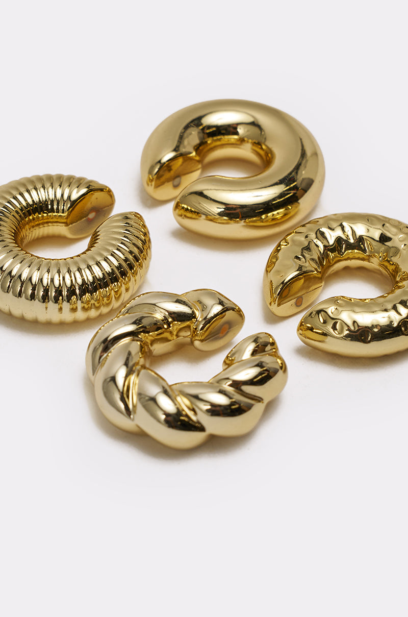 The ULTIMATE EAR CUFF SET features four gold chunky ear cuffs—smooth, ribbed, twisted, and hammered—styled on a white background for a stacked look without piercings. 3