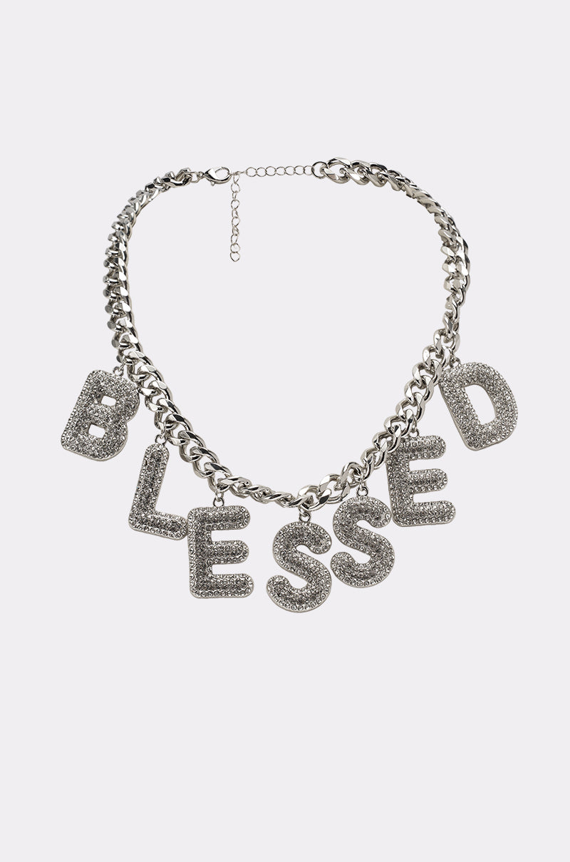 The BEYOND BLESSED NECKLACE is a chunky silver statement piece with sparkling pavé letters that spell "BLESSED." This rhinestone charm necklace stands out beautifully against any plain, light-colored background. 0