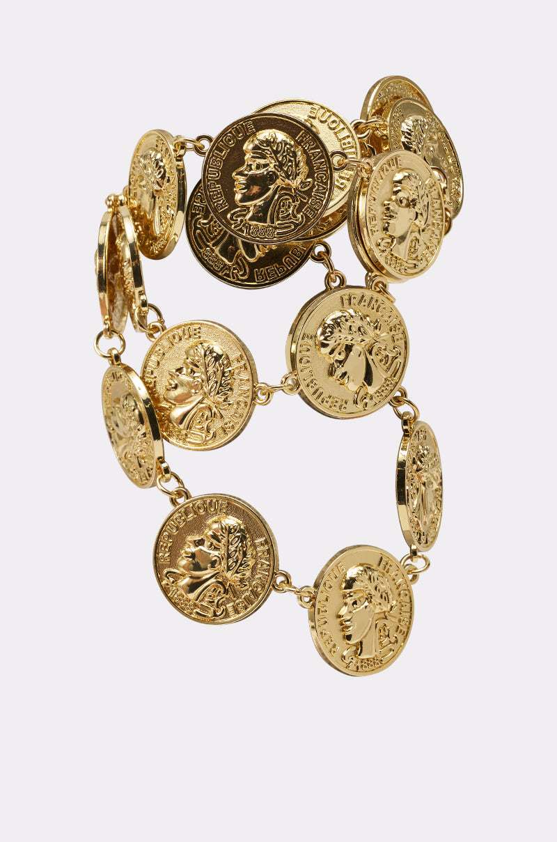 The IN MY BAG BRACELET is a vintage-glam piece with multiple gold coin-shaped charms featuring embossed profile portraits and decorative inscriptions, all linked in a circular design and shown against a plain white background. 3