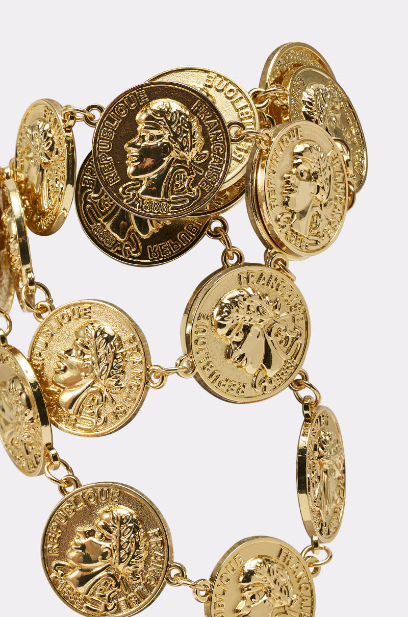 The IN MY BAG BRACELET is a vintage-inspired gold coin charm bracelet with linked coins embossed with classical profiles, "République Française," laurel wreaths, and intricate details for a timeless, statement look. 4