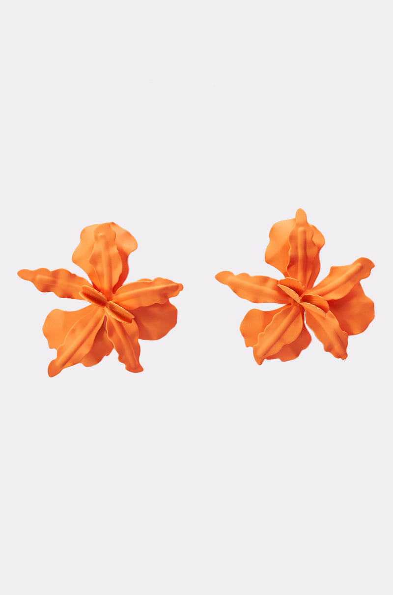 The IDK U EARRING features oversized, bright orange floral earrings with five ruffled petals each, showcased on a simple light background. 1