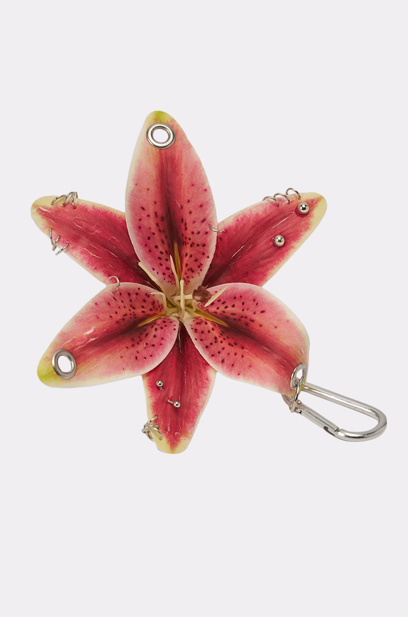The ON THE STREET PIERCED FLOWER KEYCHAIN SET features a pink lily-shaped floral charm with yellow-tipped petals, metal eyelets, and small studs—ideal for accessorizing your bag or adding stylish flair to your keys. 4