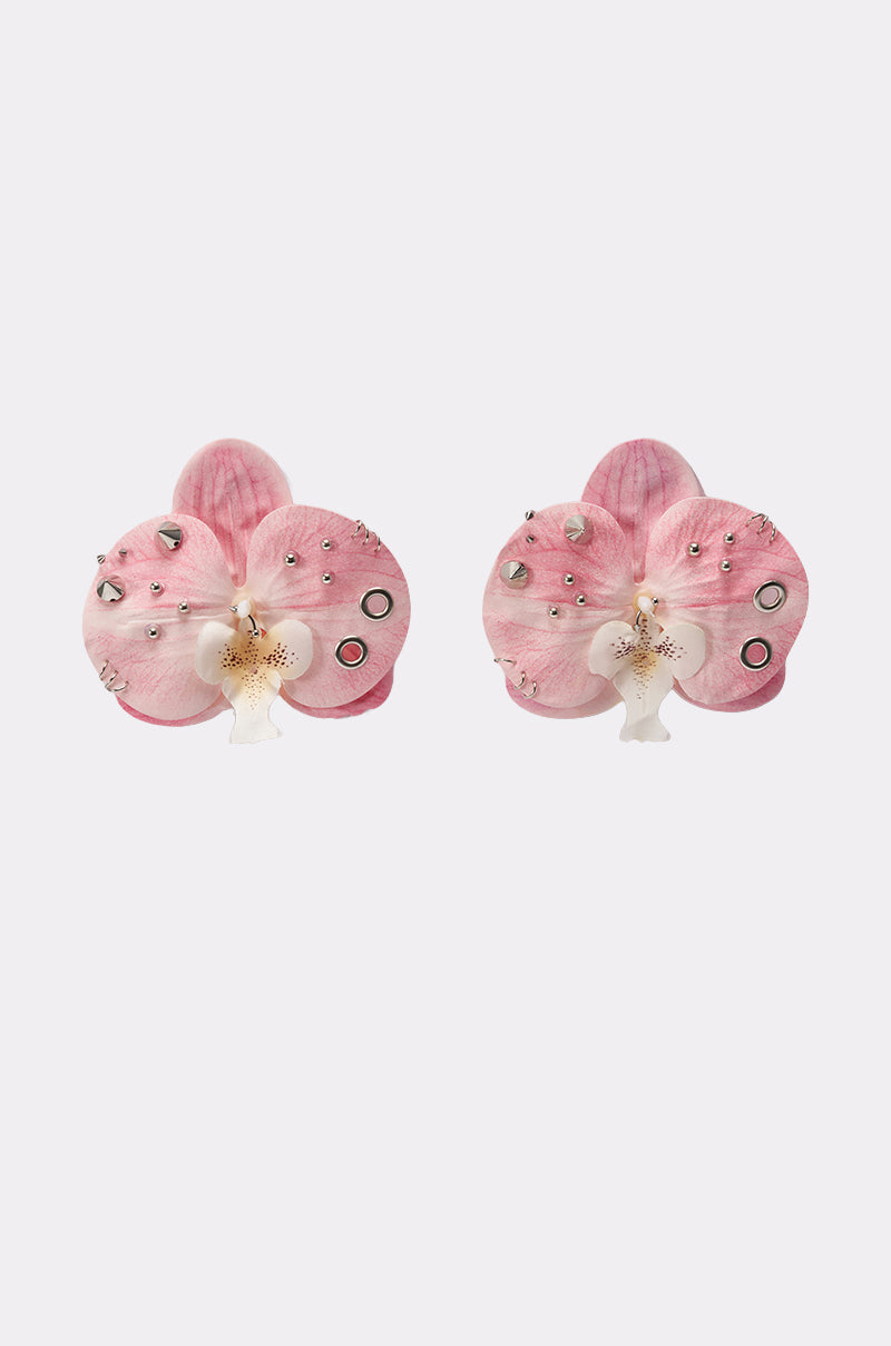 PIERCED ORCHID EARRING: Pink and white floral earrings inspired by orchids, with silver studs and black circular accents, shown on a light gray background. 0