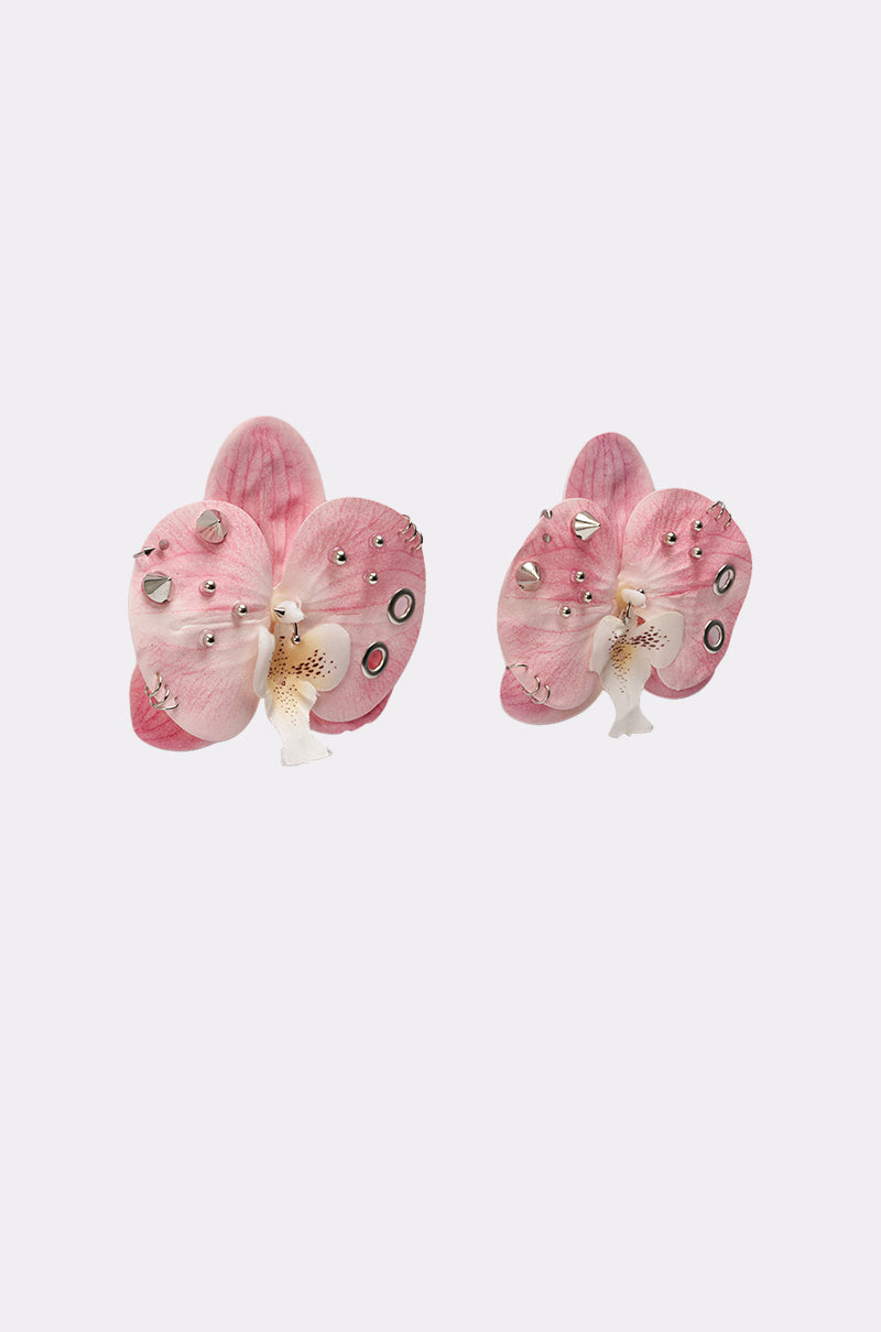 The PIERCED ORCHID EARRING features orchid-inspired pink florals with small silver studs and circular accents, showcased on a plain light gray background. 2