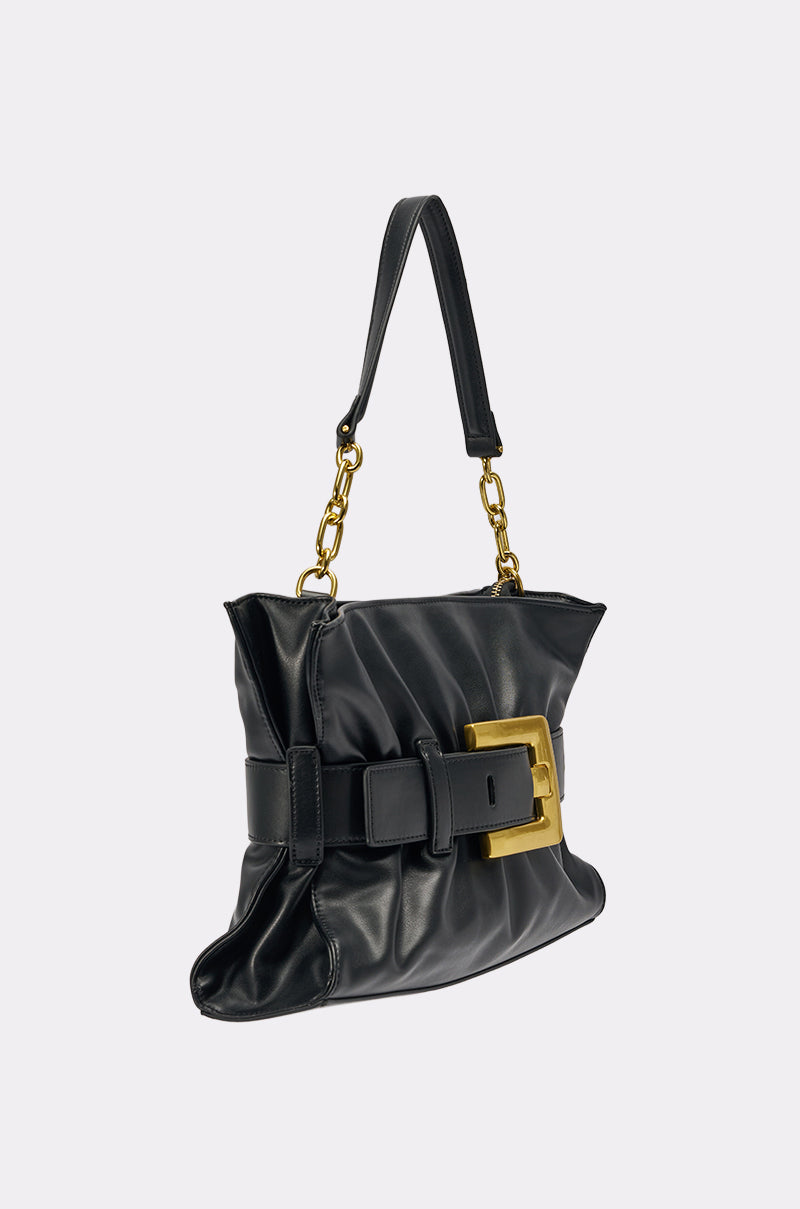 The OVERSEAS BUCKLE CLUTCH is a black faux leather handbag featuring a ruched design, statement gold buckle, and a short handle with gold chain links, set against a plain light background. 2