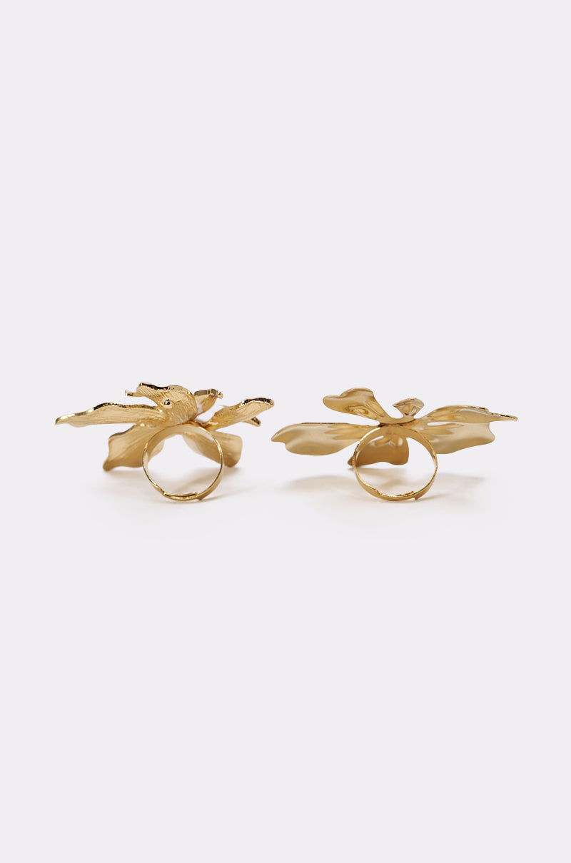 The IN BLOOM RING SET features two gold rings with bold, sculpted floral designs on top, displayed side by side against a white background—an elegant statement piece. 4