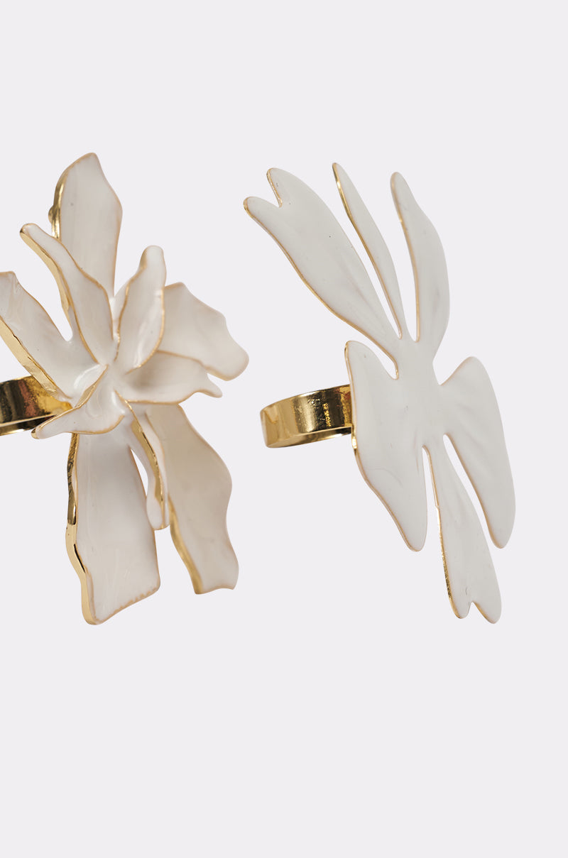 The IN BLOOM RING SET features two gold rings with bold, white enamel abstract flower designs edged in gold, displayed against a clean white background—a striking floral statement. 5