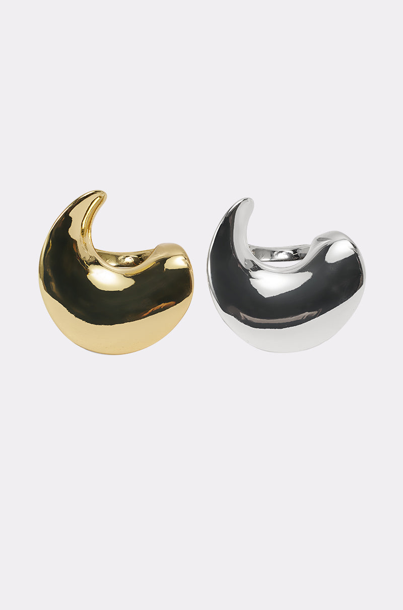 Two crescent-shaped, chunky hoop earrings—one in shiny gold, one in shiny silver—are displayed side by side on a white background, perfect for pairing with your favorite ring set or the CROSS MY HEART RING SET. 1