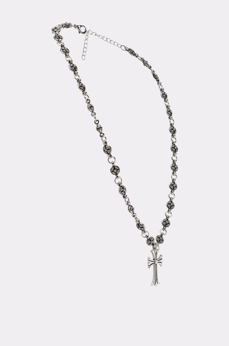 The WHATYA KNOW NECKLACE is a gothic-style silver cross necklace with an ornate link chain and detailed cross pendant, showcased on a plain light background. 3