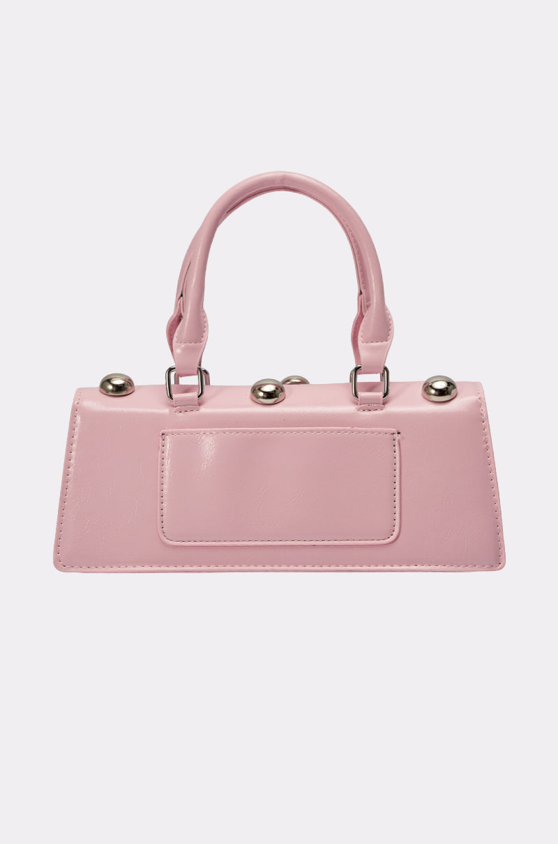The PERRI DOME EMBELLISHED PURSE is a small, rectangular pink faux leather handbag with a top handle and silver round studs on top, shown against a white background—a bold statement piece for any outfit. 4