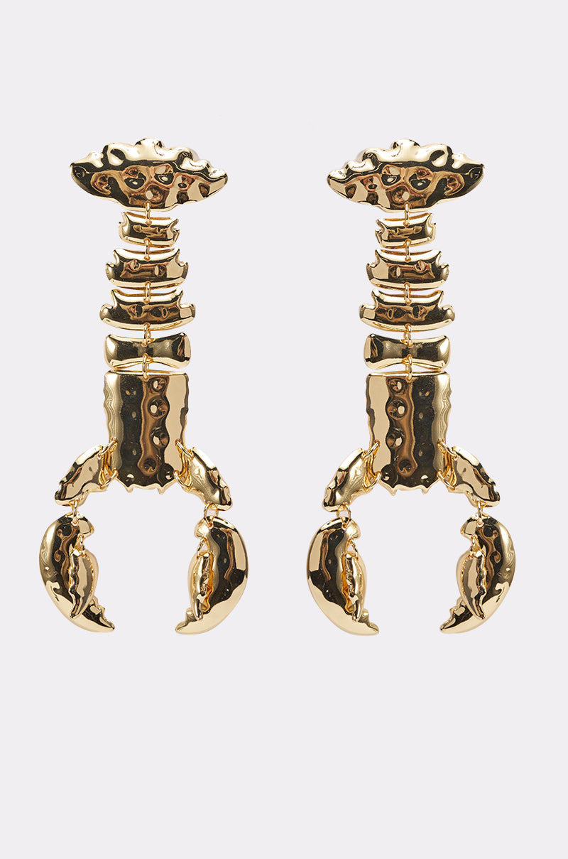 BITE ME EARRING: Gold-tone statement drop earrings with stylized segmented scorpion shapes and detailed claws, shown on a plain light background. 1