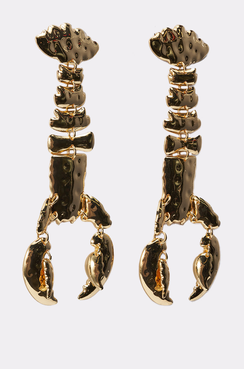The BITE ME EARRING is a pair of gold-tone statement earrings shaped like lobster claws and arms, featuring a textured, shiny metallic finish, displayed against a plain white background. 4