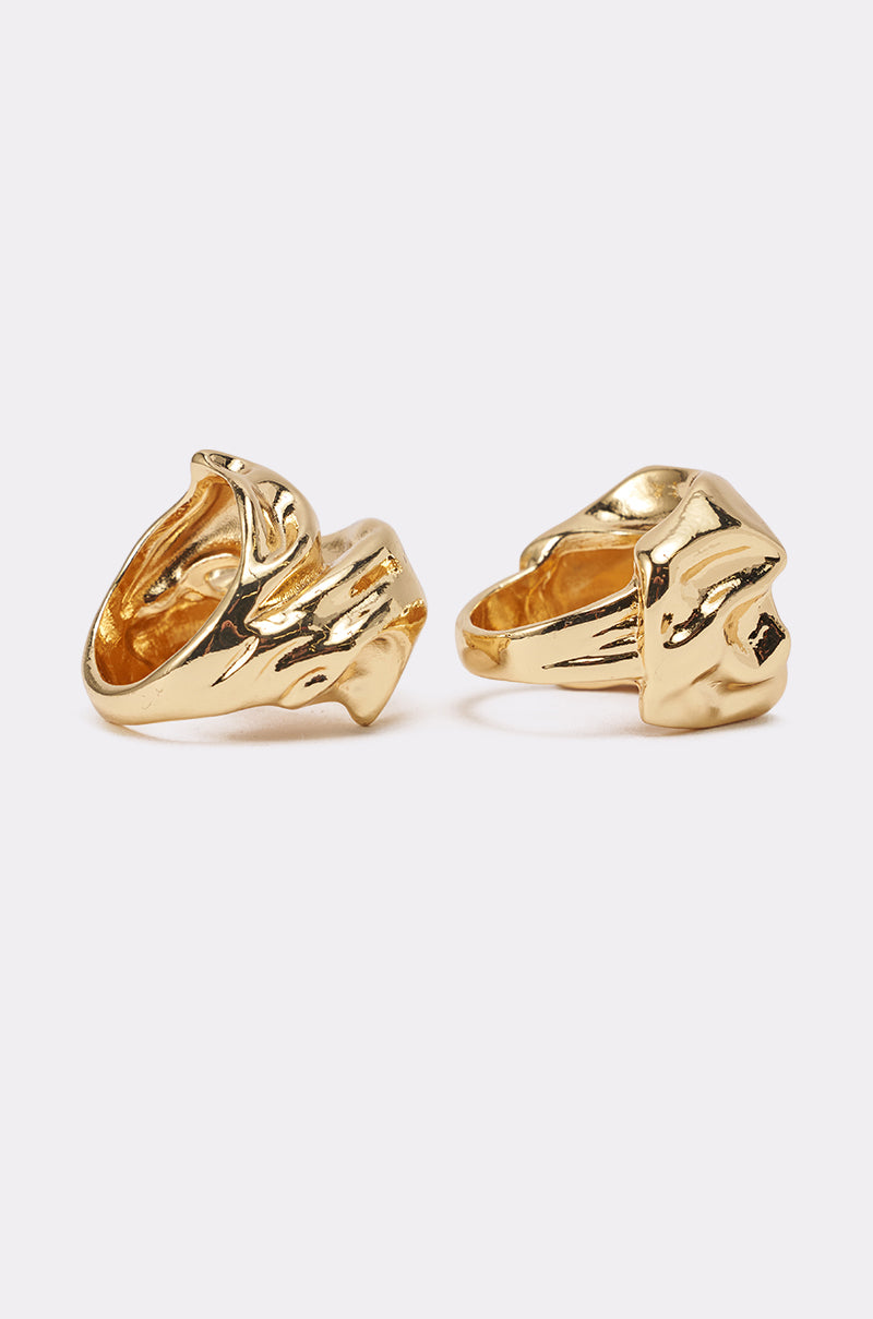 The MOLTEN DREAMS RING SET showcases two sculptural rings with a shiny, polished finish and abstract, wavy forms. Their irregular, organic shapes make them perfect for modern jewelry lovers. Displayed on a plain light background. 2