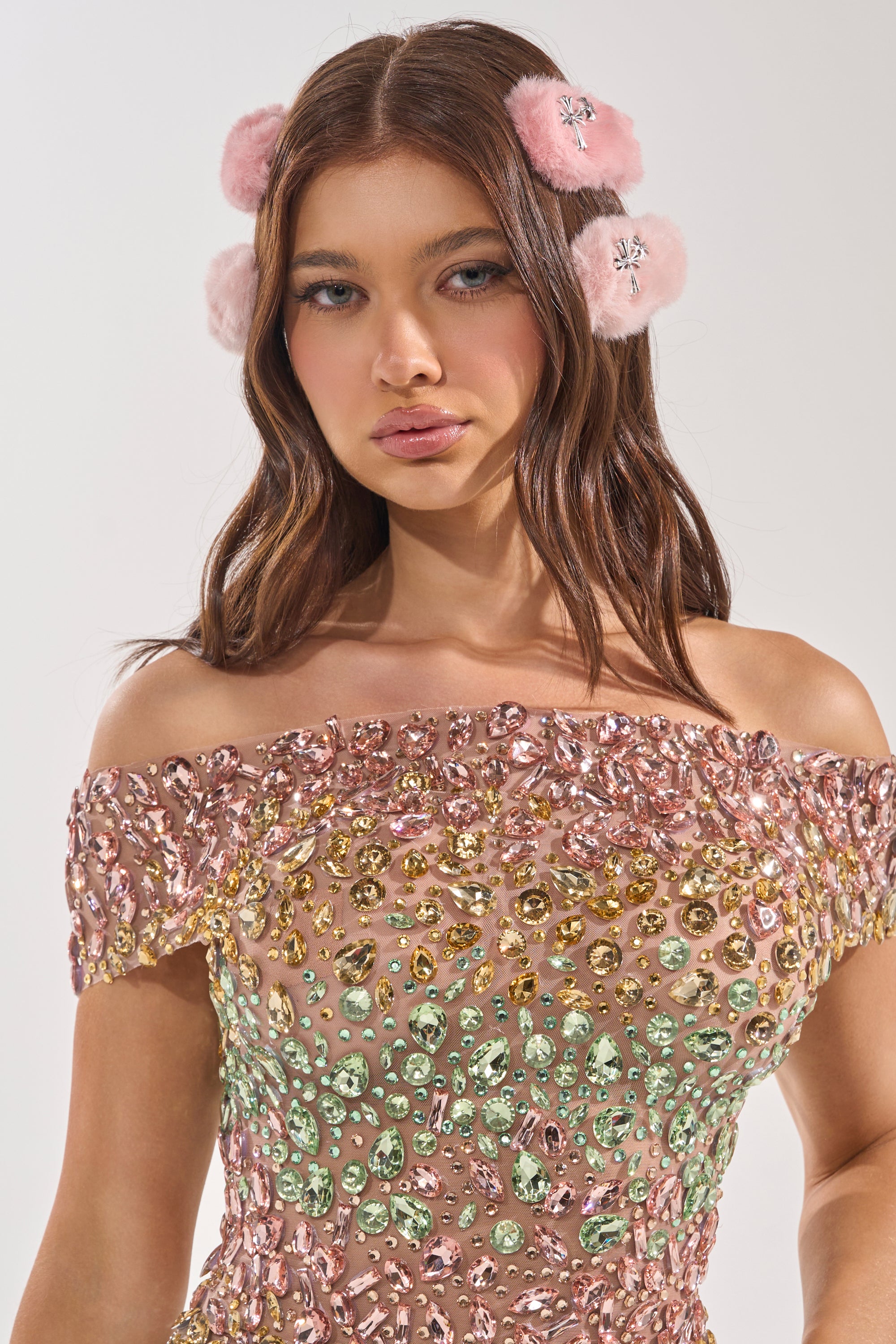 A woman with long brown hair wears a pink jeweled off-the-shoulder dress and GET IT FUR HAIR CLIPS—plush pink faux fur hair clips with small silver details—standing against a plain white background. 1