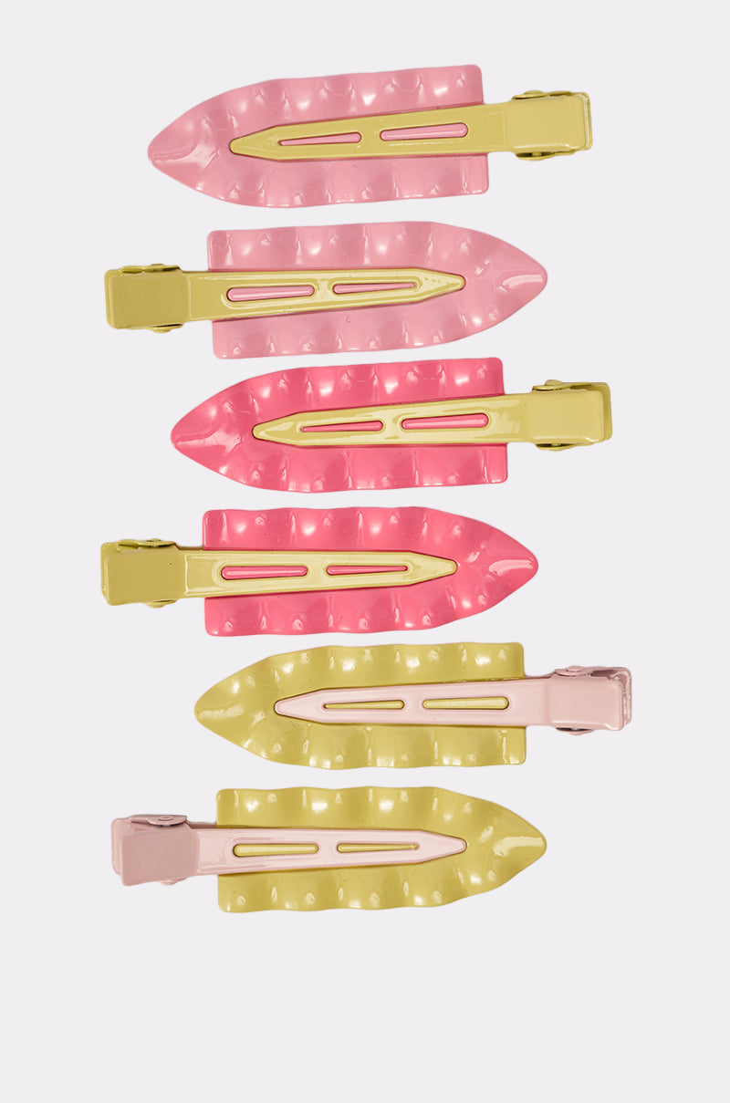 The PROUD OF U FLAT CLIP SET includes six retro enamel snap hair clips in pastel colors (2 pink, 2 dark pink, 2 yellow), arranged vertically on a white background. Each clip has a shiny finish, textured design, and secure latch end. 2