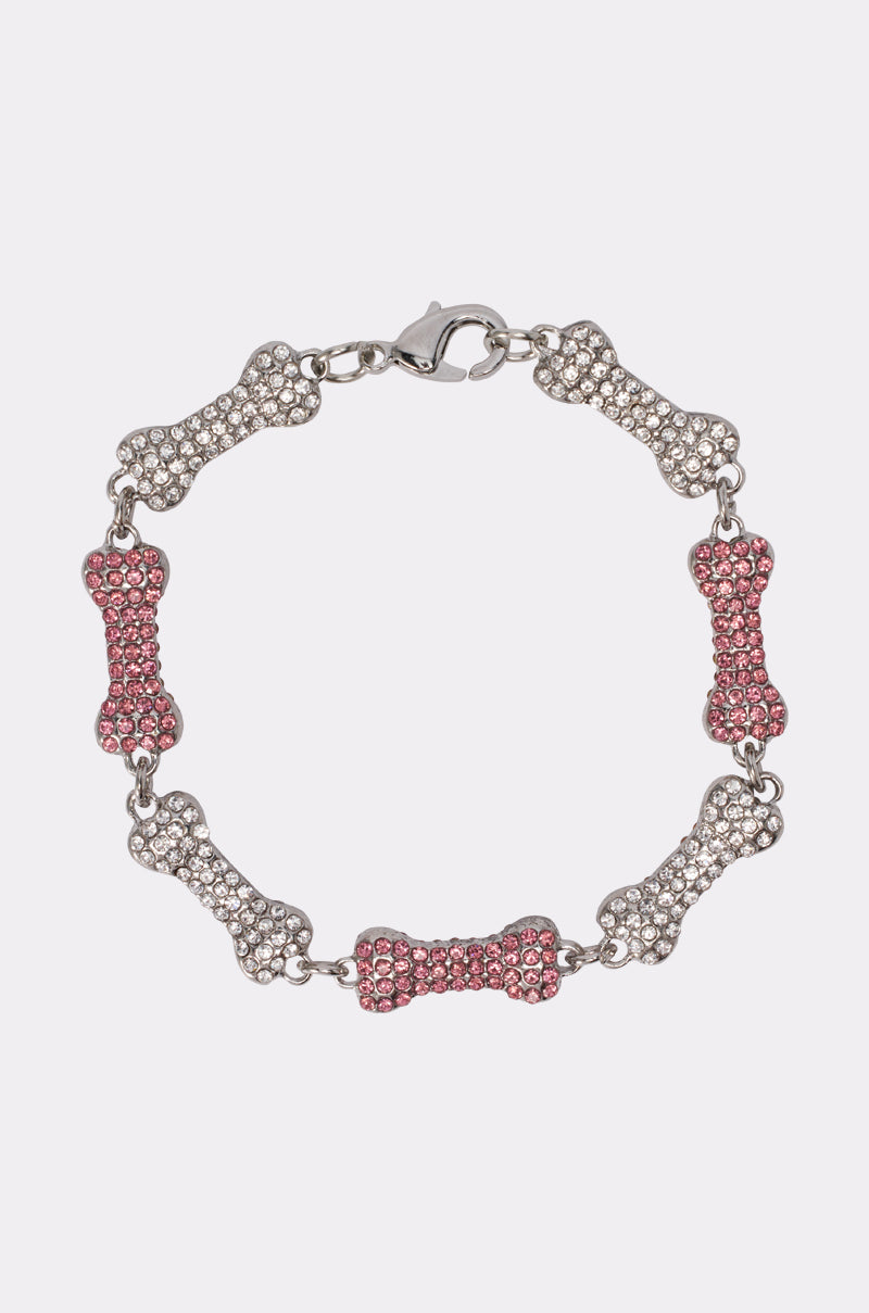 The GIVE A DOG A BONE BRACELET is a pink rhinestone bracelet with alternating silver and pink bone-shaped charms, arranged in a circle with a clasp—playful festival jewelry for dog lovers. 0