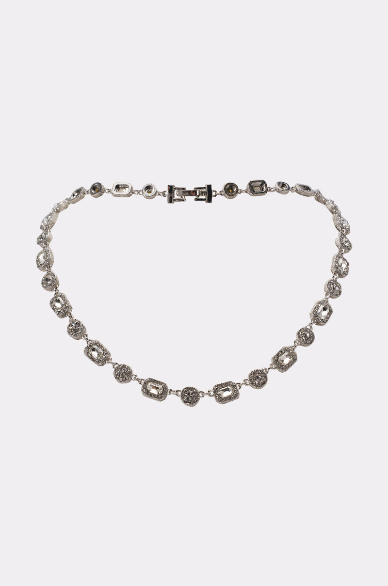 The REGAL CHAIN is a glamorous silver necklace with oval and round links adorned with sparkling stones, spaced evenly along the chain and finished with a rectangular clasp, shown on a plain white background. 0