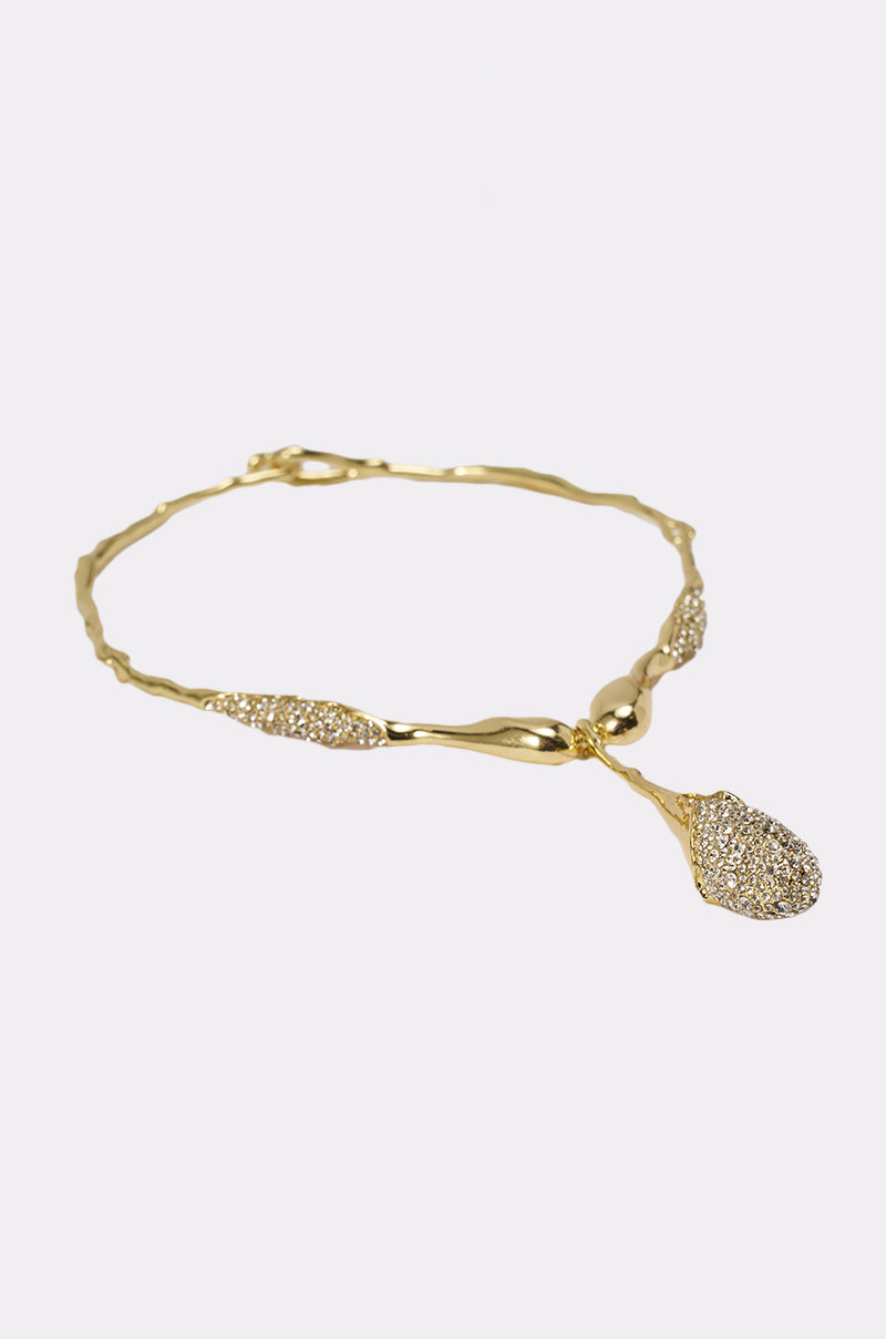 The IN YOUR DREAMS NECKLACE features a sculptural, wavy gold-tone collar with a large, sparkling irregular pendant and rhinestone accents, shown on a plain white background. 2
