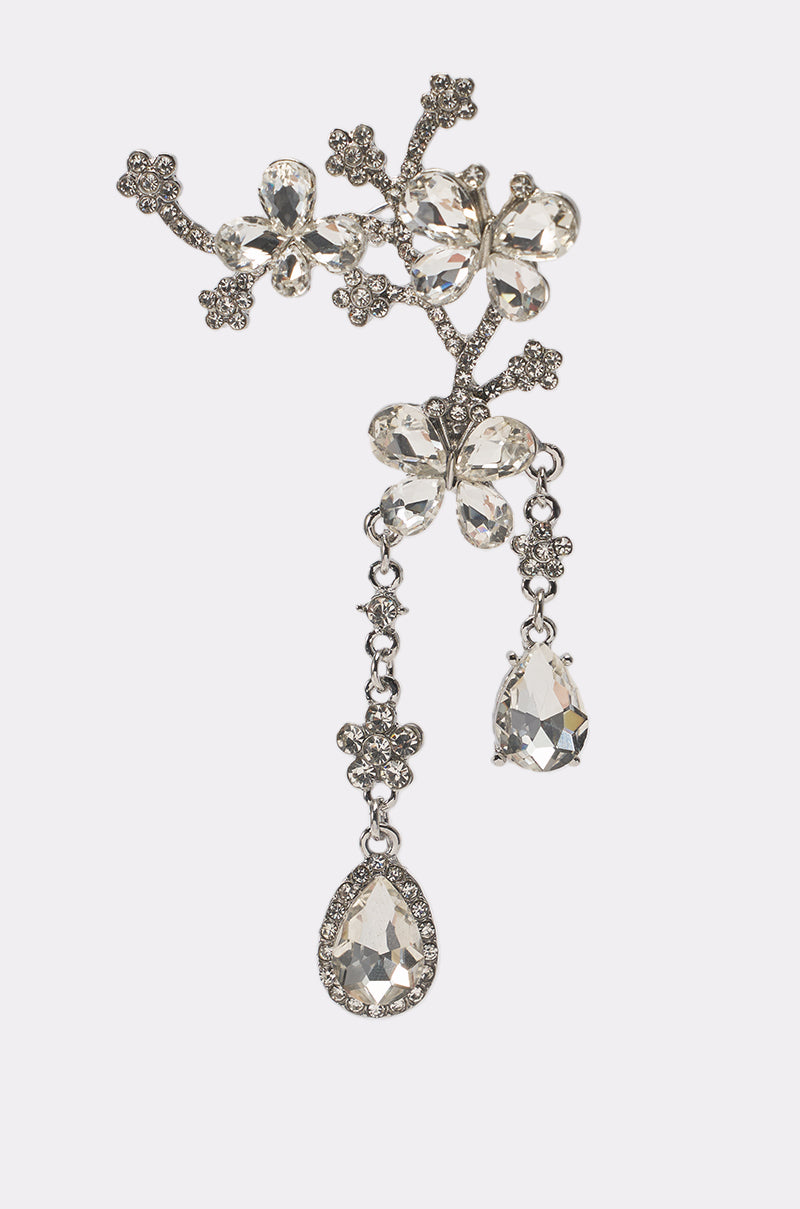 The WRAPPED AROUND EARRING features sparkling silver with crystal flowers, leaf motifs, and two dangling teardrop pendants, evoking floral drop elegance. Perfect for formal occasions. Displayed on a plain white background. 3