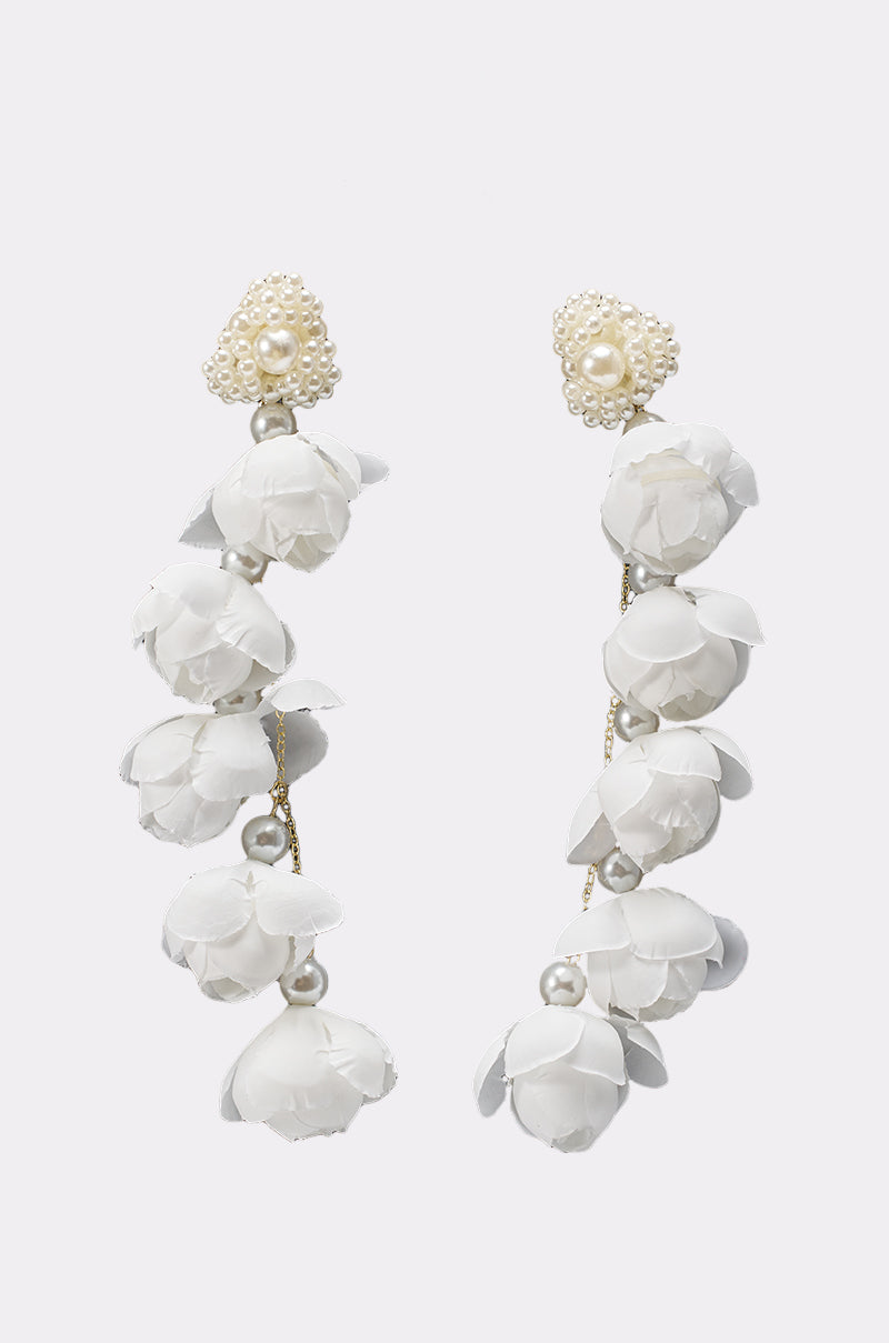 The LETS BLOOM DANGLE EARRING IN WHITE features elegant floral petals and pearl accents in a cascading design, making these pearl dangle earrings perfect for a stunning bridal look against a light background. 1