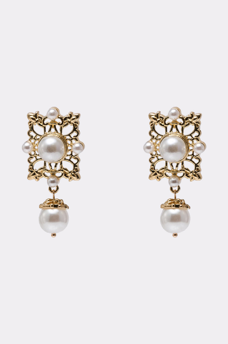 The REGENT VIBE EARRING is a pair of ornate gold-tone earrings with filigree details, showcasing central and dangling round white pearls, accented by smaller pearls, set against a light background. 0
