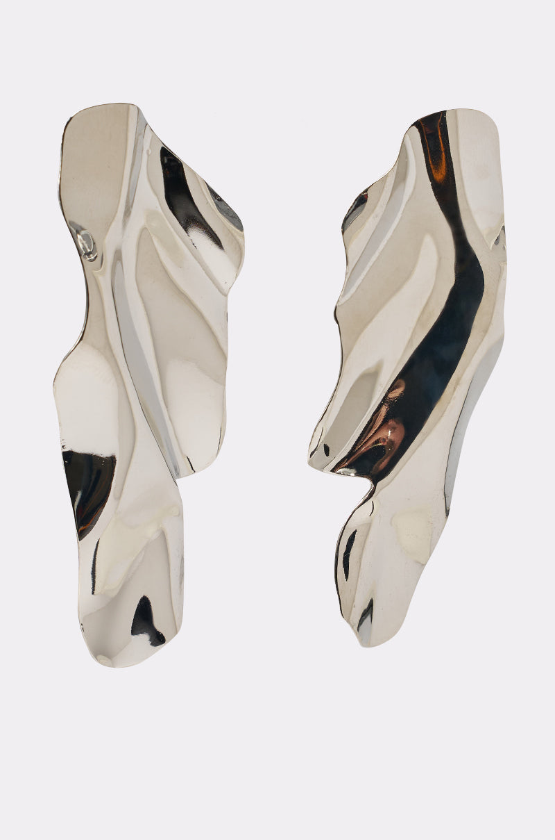 The CHROME GAL EARRING features abstract, asymmetrical silver with a wavy, sculptural design that reflects light and forms organic shapes, embodying liquid metal allure against a plain white background. 2