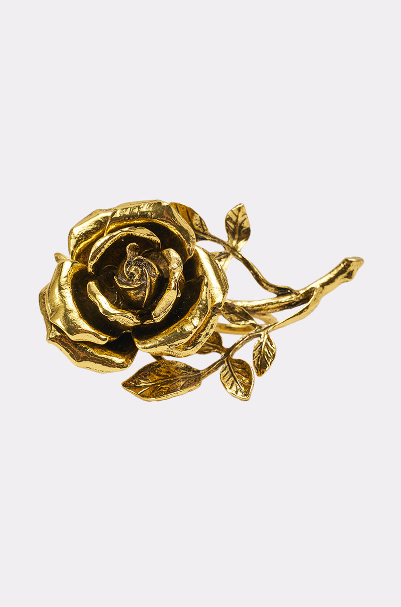 The IN BLOOM COCKTAIL RING features a detailed golden rose with leaves and stem, echoing rose elegance, showcased against a plain white background. 1