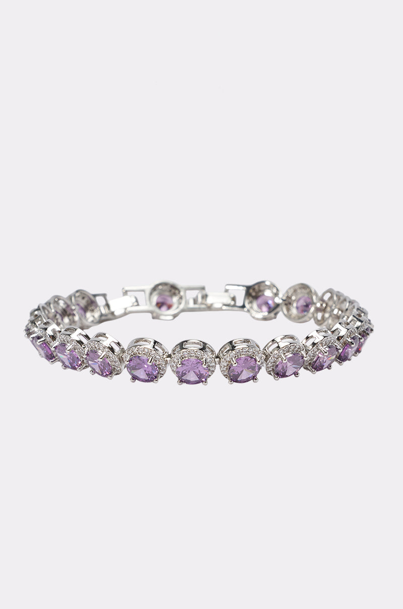 The PLUM PLS CZ BRACELET is a silver-tone bracelet showcasing round, faceted plum-colored CZ stones in individual prongs, set against a plain light background.