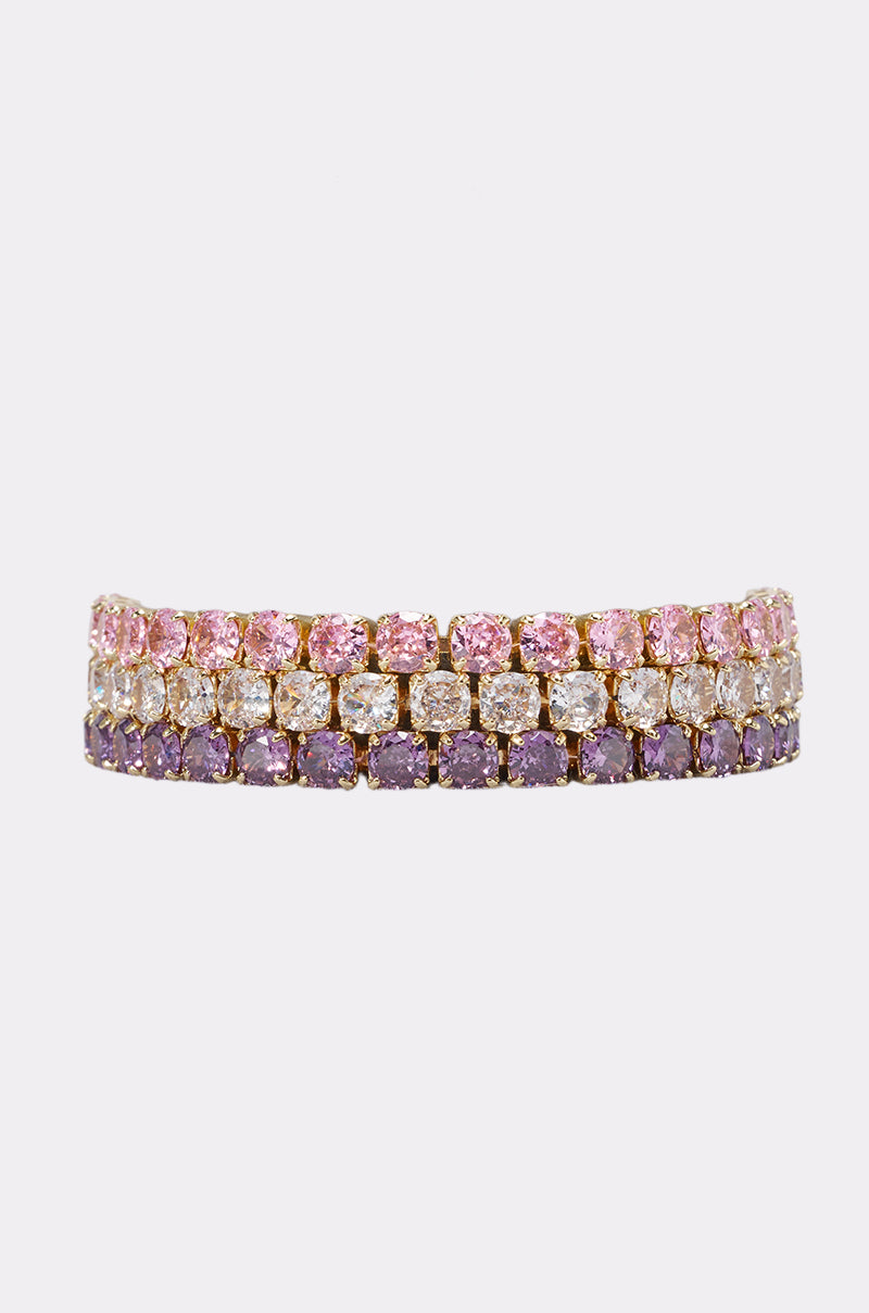 The IT GIRL BRACELET SET features a gold-tone tennis bracelet with three rows of pink, clear, and purple gemstones that sparkle beautifully on a light background—an ideal choice for any dazzling bracelet collection.