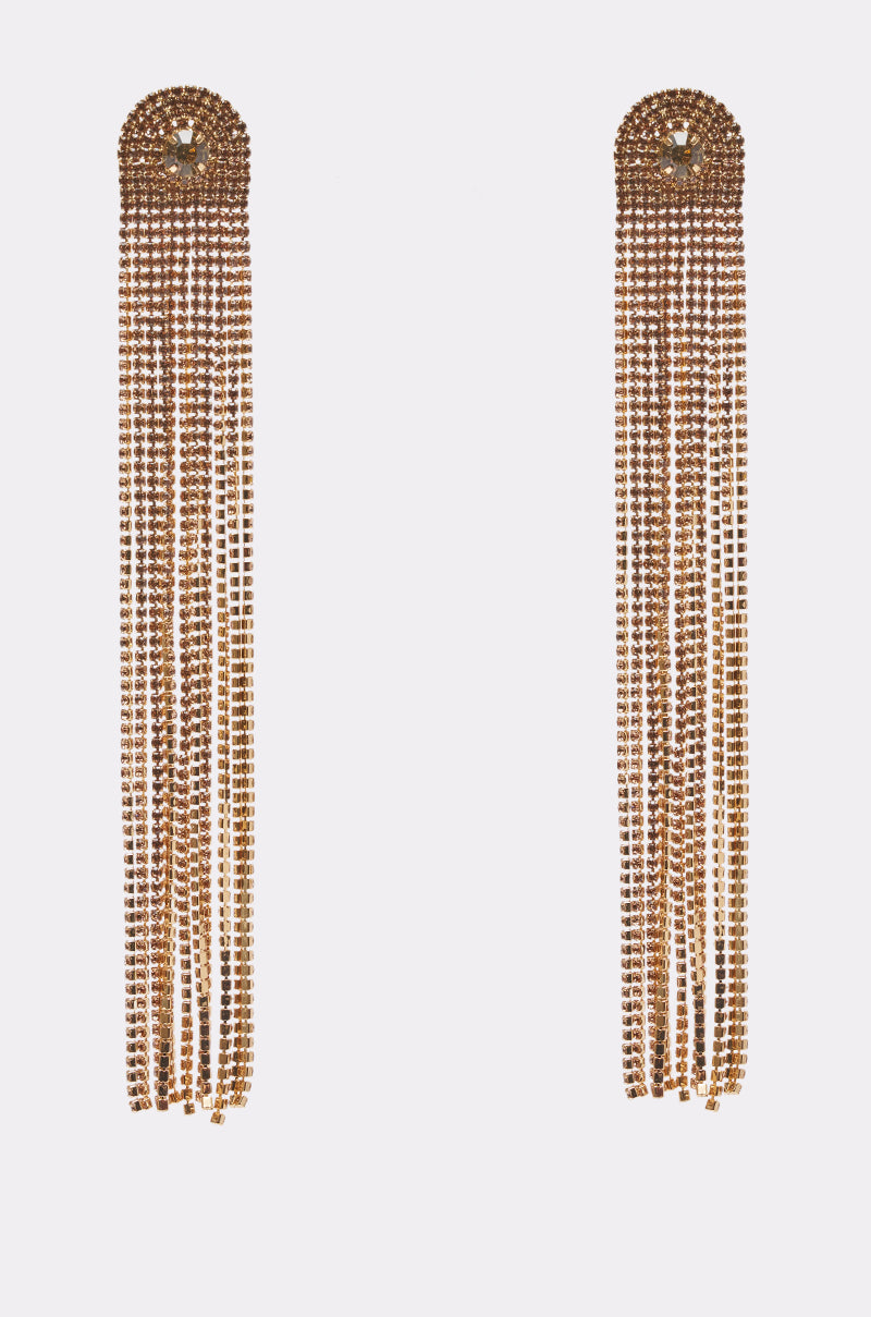 The ROARING 20S EARRING features long, gold-tone chandelier drops with sparkling rhinestones in straight, uniform rows, evoking vintage-chic glamour against a plain white background.