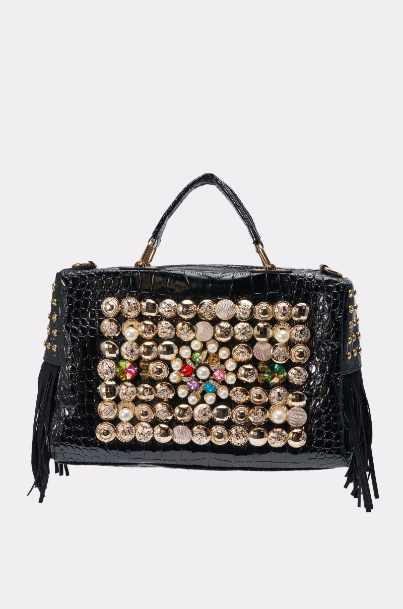 The TAYTAY EMBELLISHED PURSE is a black croc faux leather bag featuring gold and jewel-studded front embellishments, gold studs, chic black fringe on each side, and a short top handle.