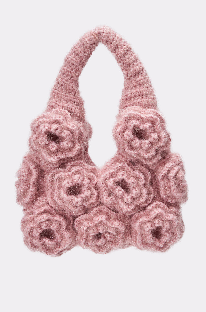 The FLORETS CROCHET PURSE is a soft pink knit handbag with bold 3D floral rosette details on the front and a wide, textured handle.
