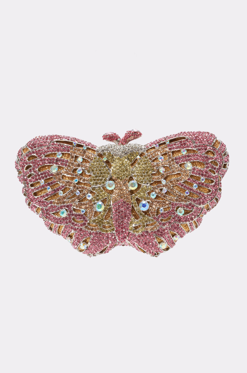 The FLY AWAY BLING LUXE CLUTCH shines with pink, gold, and silver rhinestones plus sparkling crystal accents in a jeweled butterfly shape, evoking elegance on a classic white background.