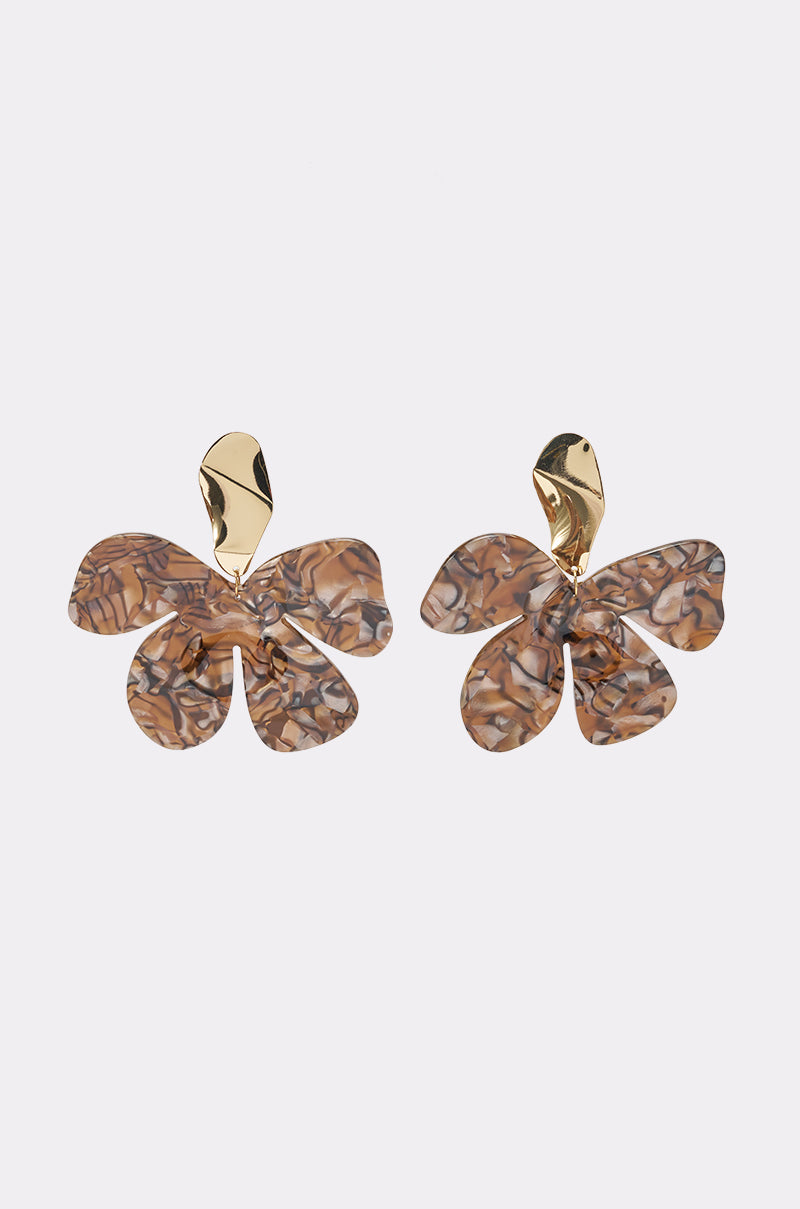 The MIXED EMOTIONS FLOWER EARRING is a pair of statement earrings featuring gold-tone metal tops and marbled floral acrylic drops in shades of brown, beige, and gray, accented with a subtle touch of gold, and displayed on a light background.