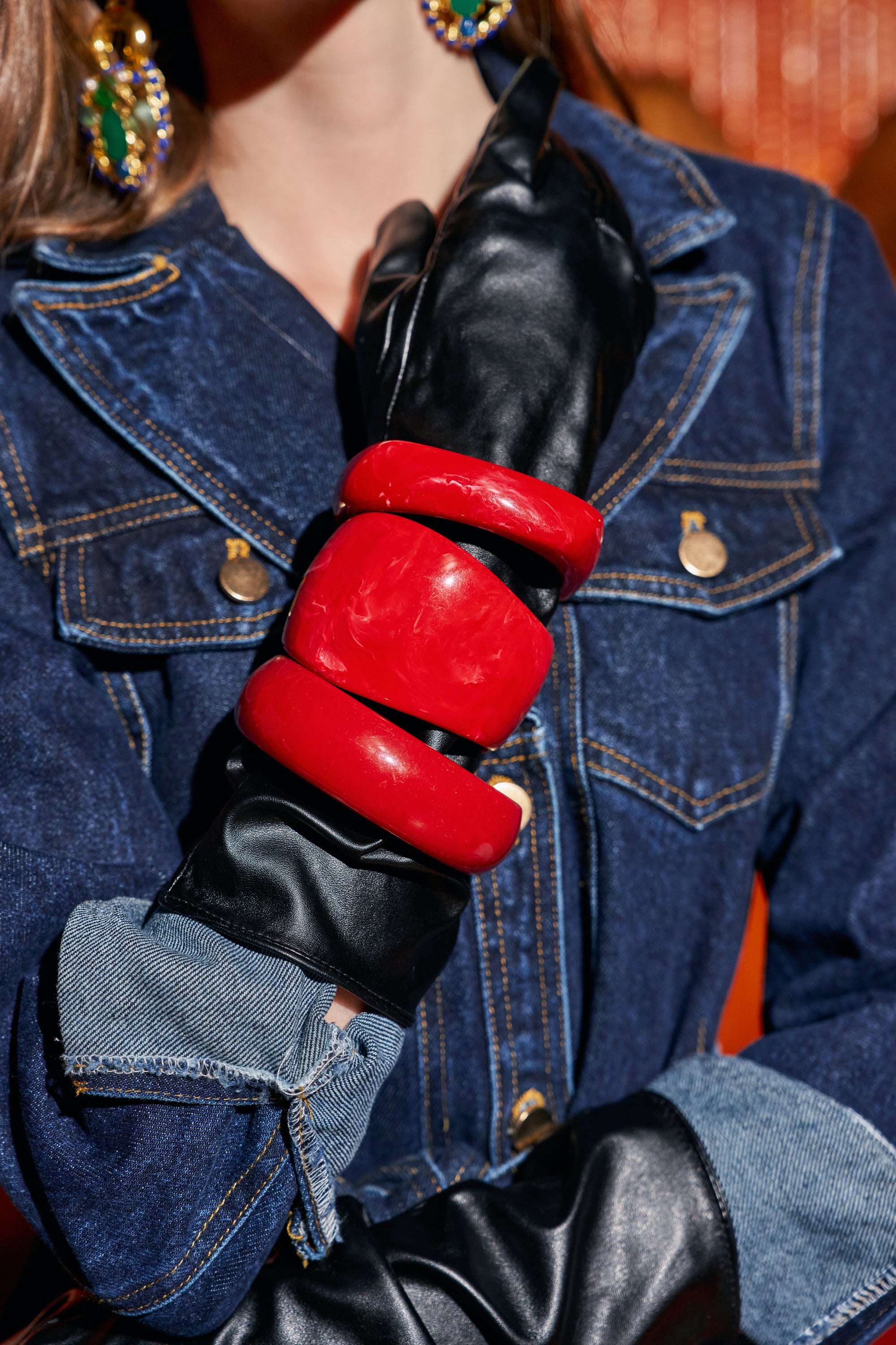ON FIRE BANGLE SET featuring three wide, bright red resin bangles worn over a black leather glove and a denim jacket.