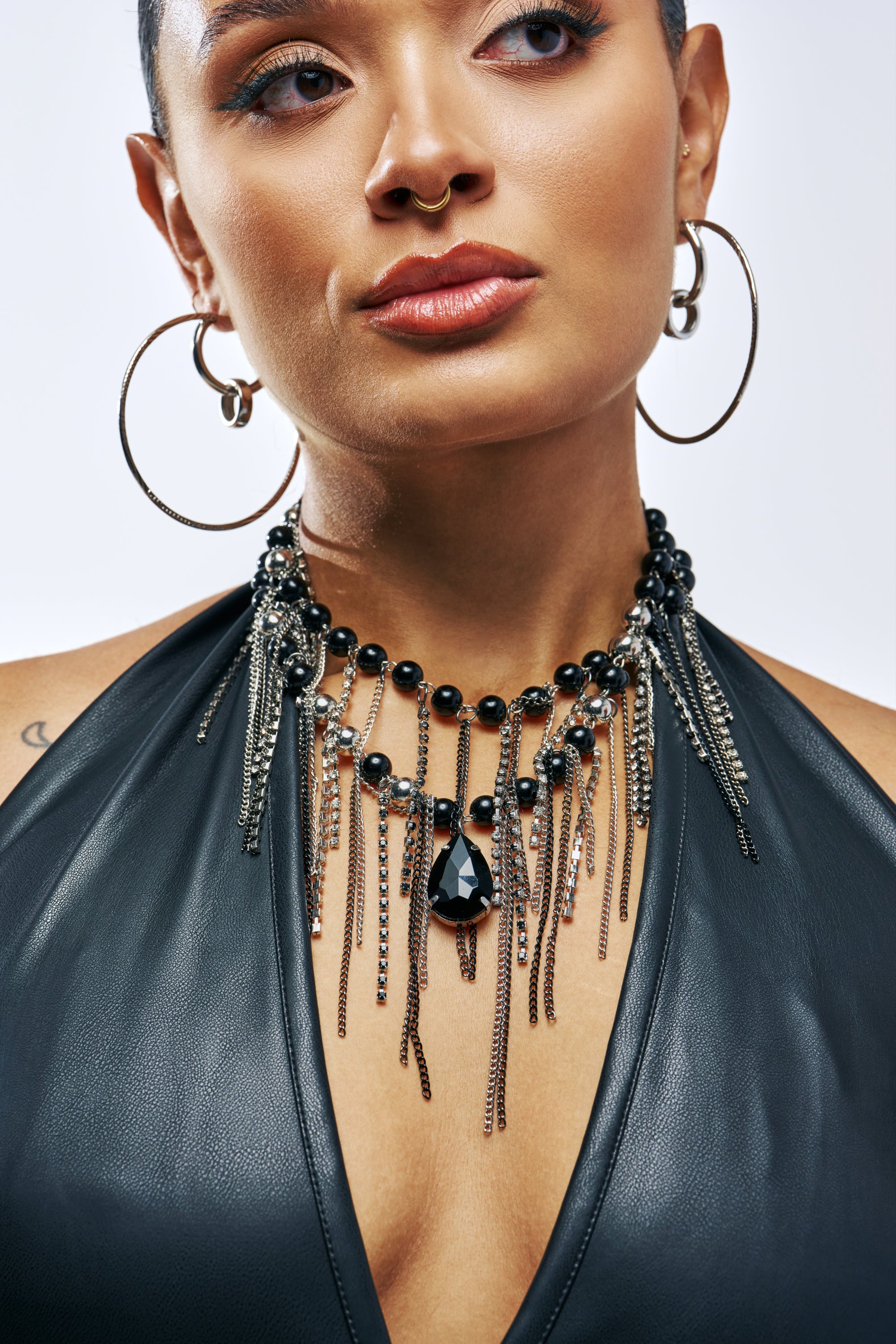 The ONYX DRIP NECKLACE is a layered necklace featuring black beads, silver-tone chains, and a central black teardrop pendant.