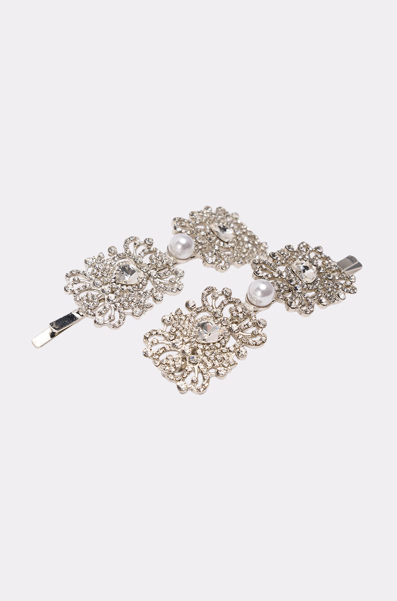 The REGENCY HAIR CLIP SET features two ornate silver crystal hair clips adorned with rhinestones and faux pearls, displayed on a plain white background. 3