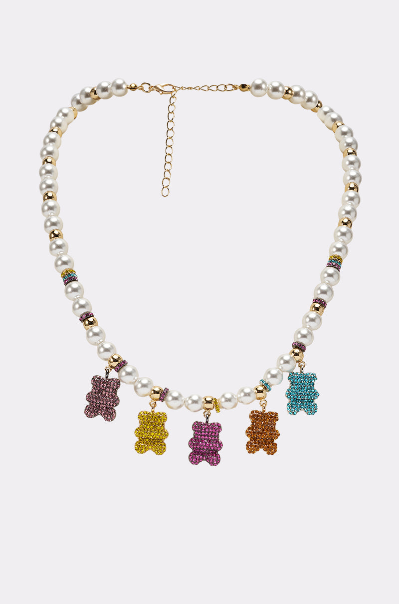 The LUXE BEAR CHARM NECKLACE is a faux pearl necklace with gold accents, featuring five gummy bear pendants in purple, yellow, pink, orange, and blue on a plain light background. 1
