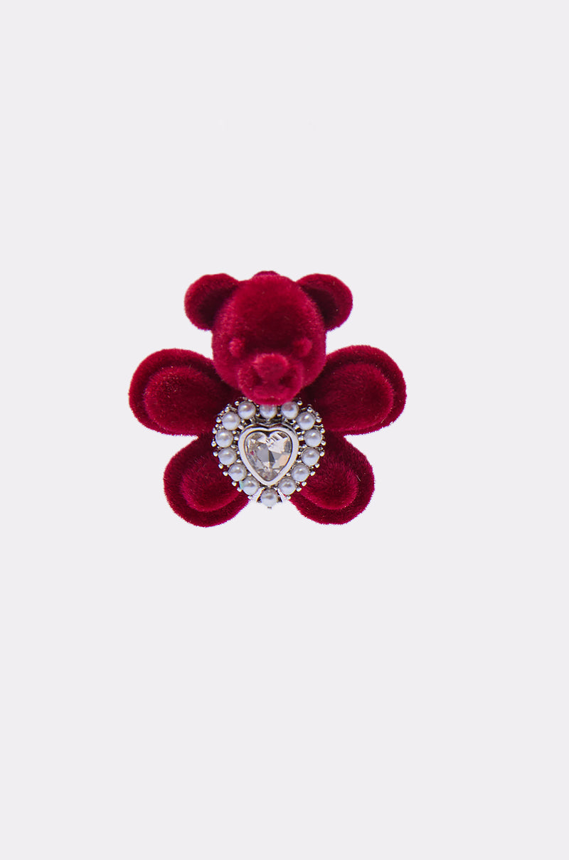 The HUG ME EARRING set includes plush deep red teddy bear brooches with petal-shaped limbs and a heart-shaped gem framed by pearls on the chest, paired with matching velvet stud earrings, all shown against a simple light background. 3