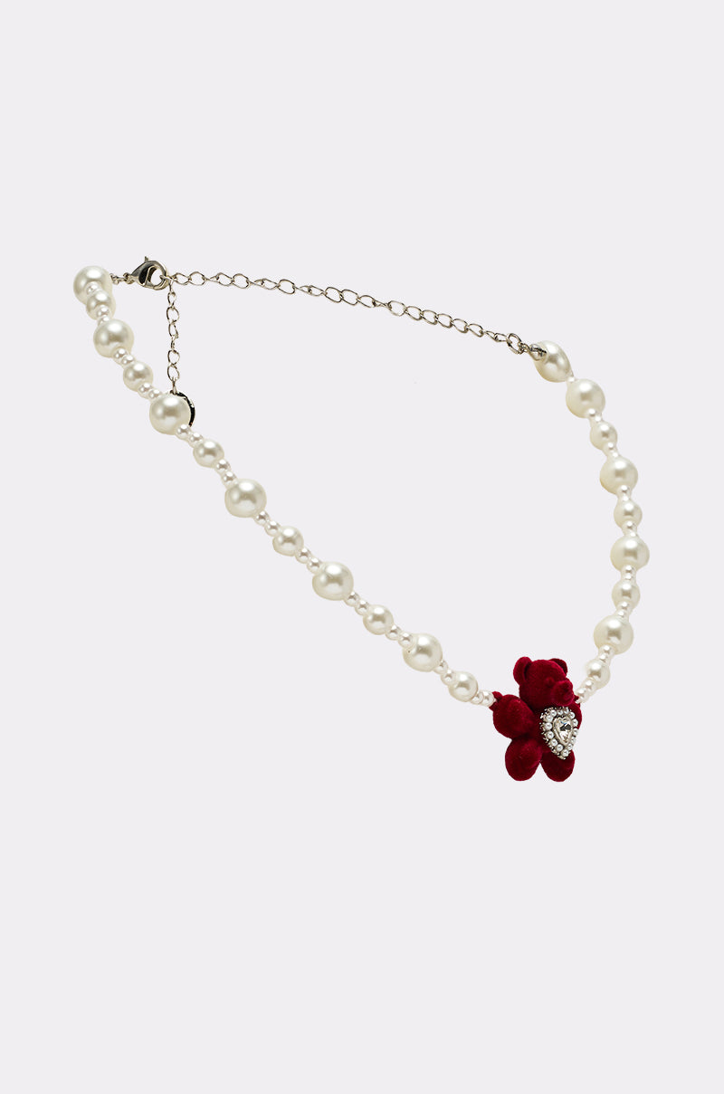 The HUG ME NECKLACE, adorned with a delicate red flower, brings a touch of elegance to any outfit.