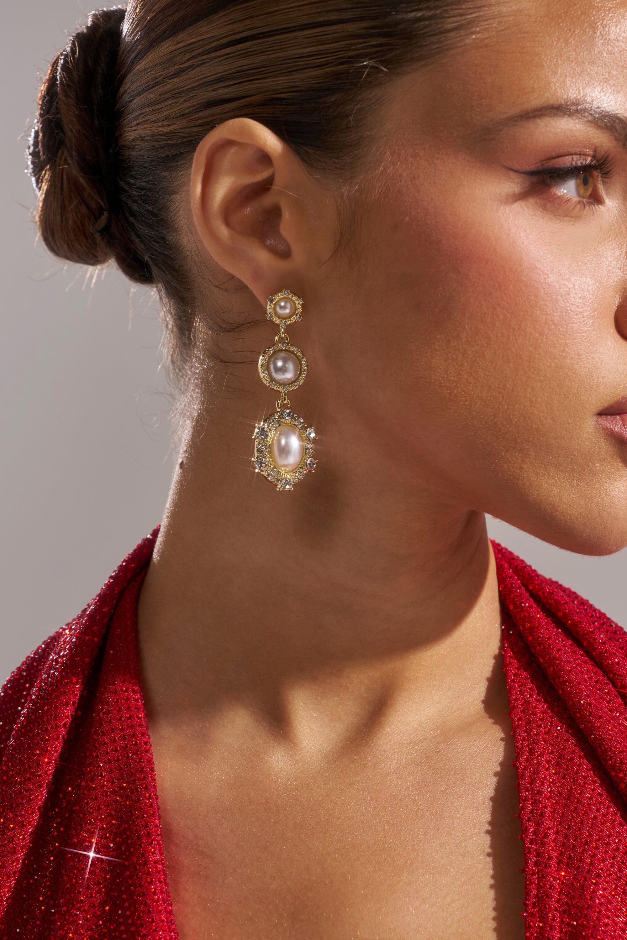 A woman styled in a sleek bun models the REGENCY EARRING, showcased in close-up from the side against a neutral background. 4