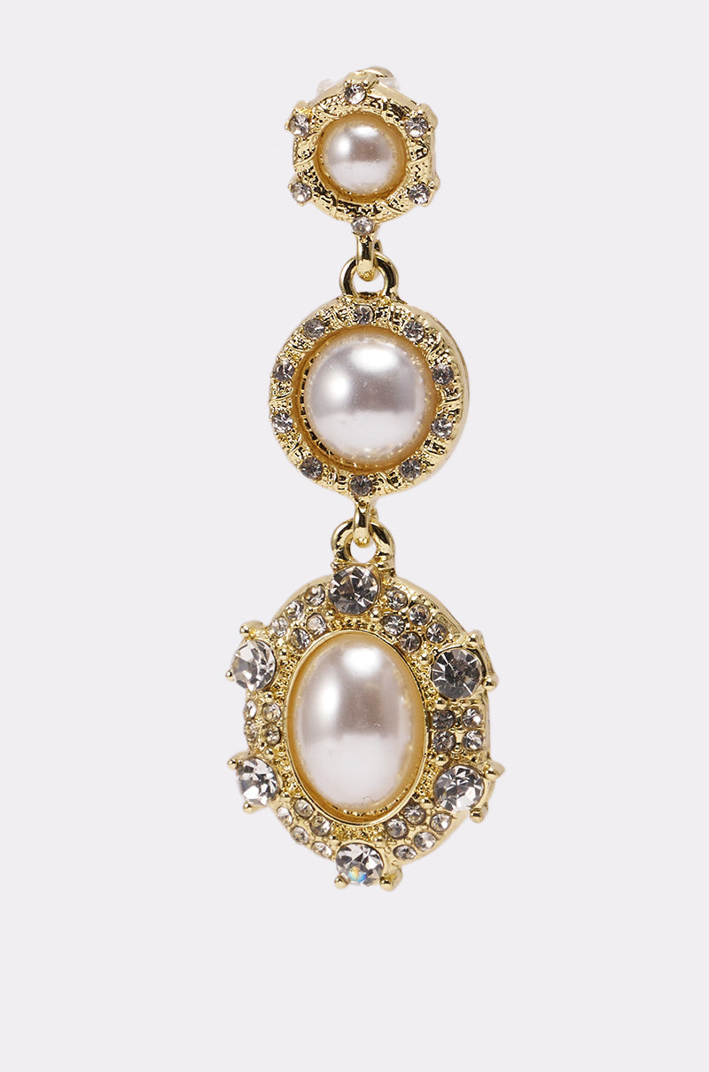 The REGENCY EARRING showcases three large pearls, each encircled by clear sparkling stones in a decorative setting, arranged vertically against a plain white background. 6