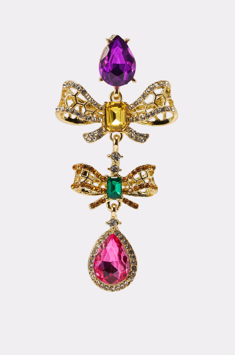 The LUXE BOW EARRING dazzles with crystal-encrusted bows, accented by a large purple gem on top, yellow and green stones in each bow, and a bold pink teardrop at the bottom—all surrounded by sparkling clear crystals. 3